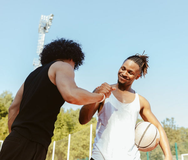 Two friends fist-bumping on a basketball court
